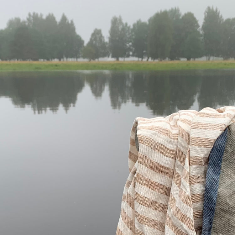 Badetuch Regnbåge aus Leinen in ziegelrot/sand auf Geländer am See