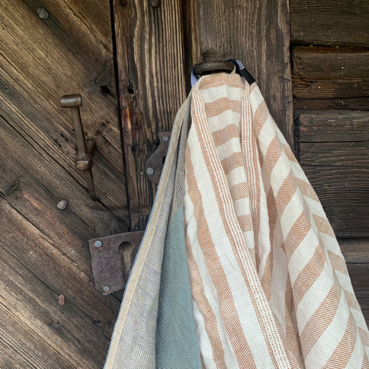 Badetuch Regnbåge aus Leinen in ziegelrot/sand an der Tür einer Härbre