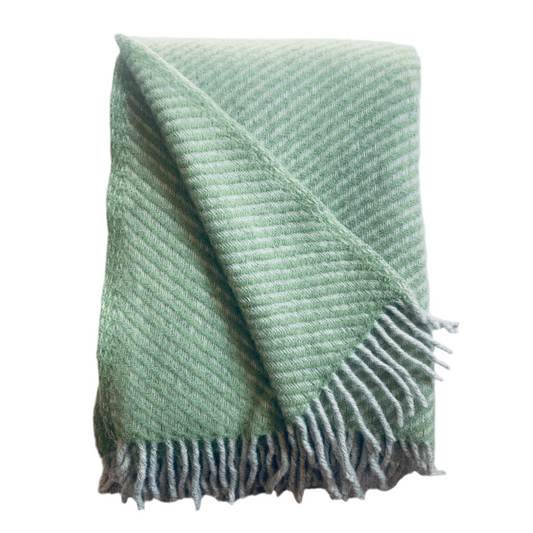 Wolldecke aus Lammwolle Carl grau mit dicken grauen Fransen zusammengefaltet mit aufgeschlagener Ecke vor neutralem Hintergrund