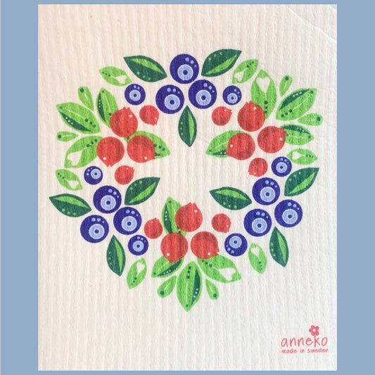 Illustrierter Kranz aus Blaubeeren und Preiselbeeren und grünen Blättern, in der unteren rechten Ecke steht das Logo von Anneko