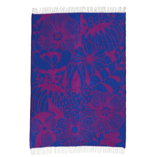 aufgefaltete Wolldecke, sodass man schön alle Blumen und Blätter in lila auf dunkelblauem Hintergrund sieht