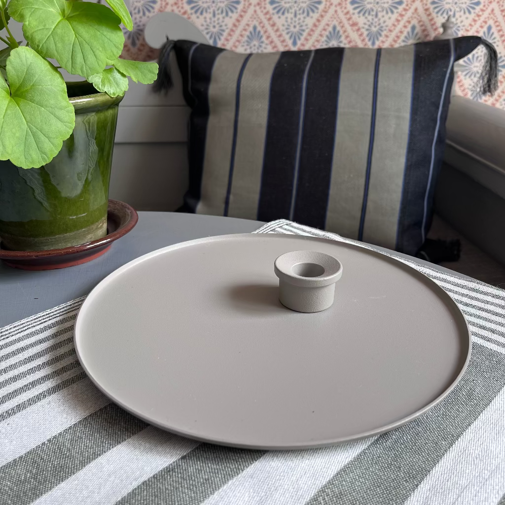 Kerzenteller und Kerzenhalter kalk in romantischem Setting auf Tisch mit Pelargonie