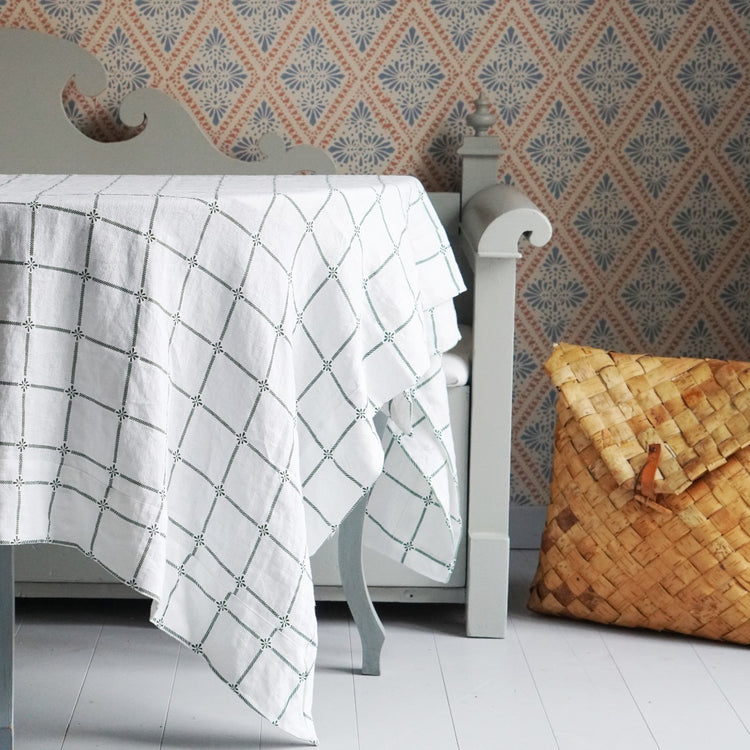 Tisch mit Tischdecke vor Küchenbank, daneben steht ein Birkenrindenrucksack