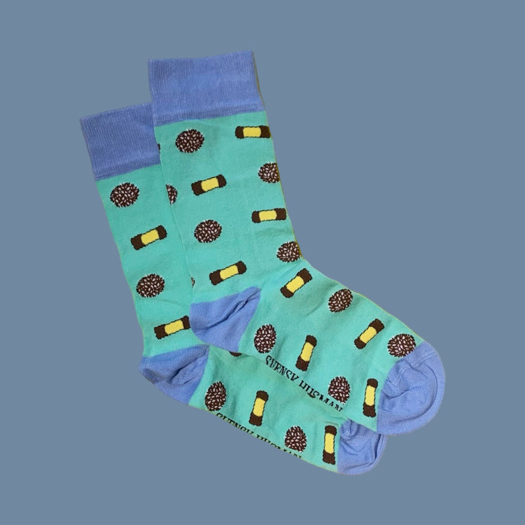 zwei Socken in grün mit blauem Bündchen, Ferse und Zehenspitze mit Punschrollen und Schokobällen drauf