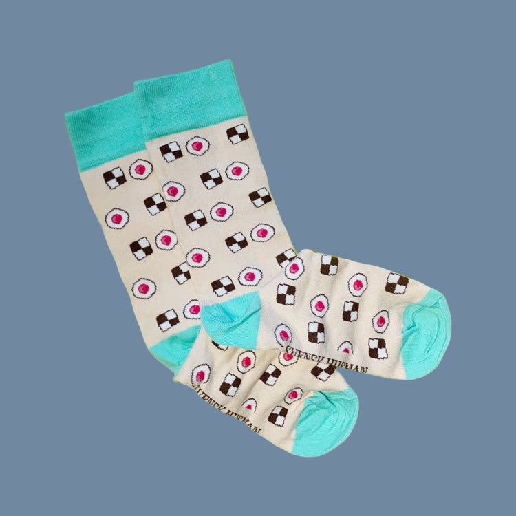 zwei Socken in beige mit grünem Bündchen, Ferse und Zehenspitze mit Keksen und Himbeerhöhlen drauf