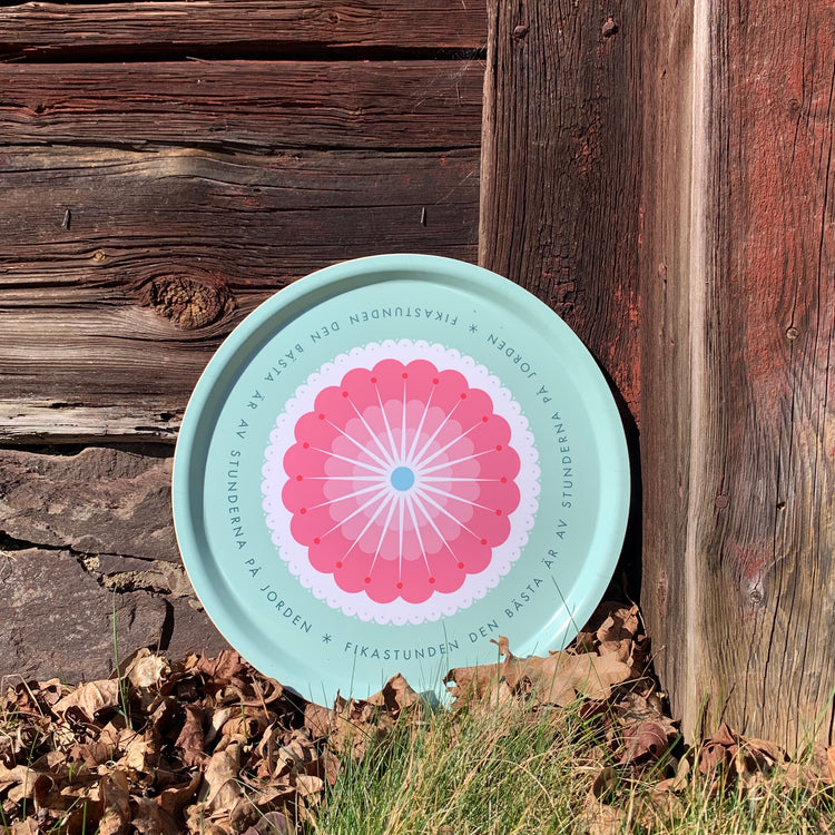 Rundes Tablett „Fikastund“ lehnt außen an roter Holzhauswand