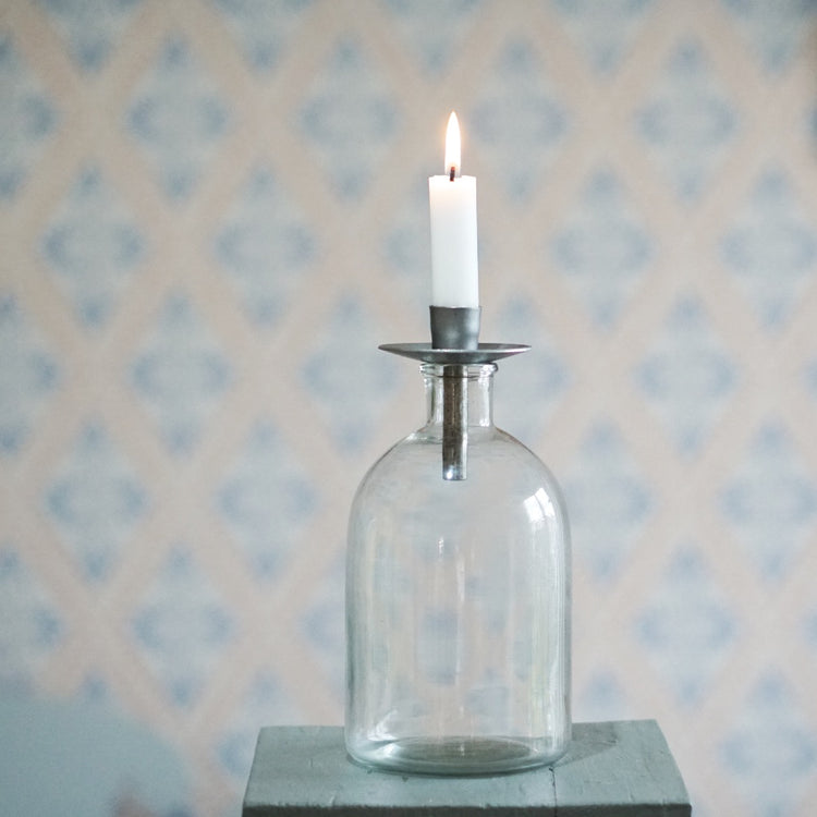 Kerzenhalter Flaska schmal aus Metall unbehandetlt auf einer Flasche mit brennender Kerze