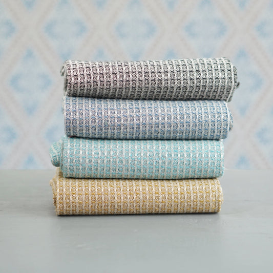 vier Handtücher Bubbel aus Leinen im Stapel vor Schwedentapete