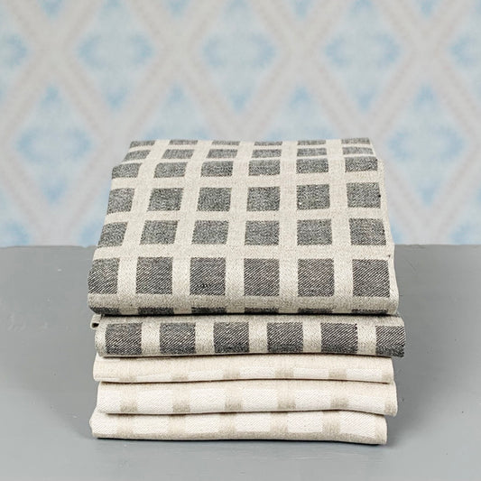 Handtuch aus Leinen Ruta natur und schwarz als Stapel vor Tapete im Laden