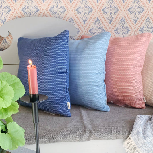 Kissen Heavy Weave in zwei Tönen Blau, Rosa auf Küchensofa mit Kerze im Vordergrund