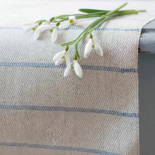 Högbo Tischläufer aus Leinen mit schmalen blauen Querstreifen auf Tisch mit Schneeglöckchen