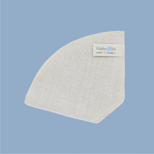 Kaffeefilter aus Leinen liegend vor hellblauem Hintergrund