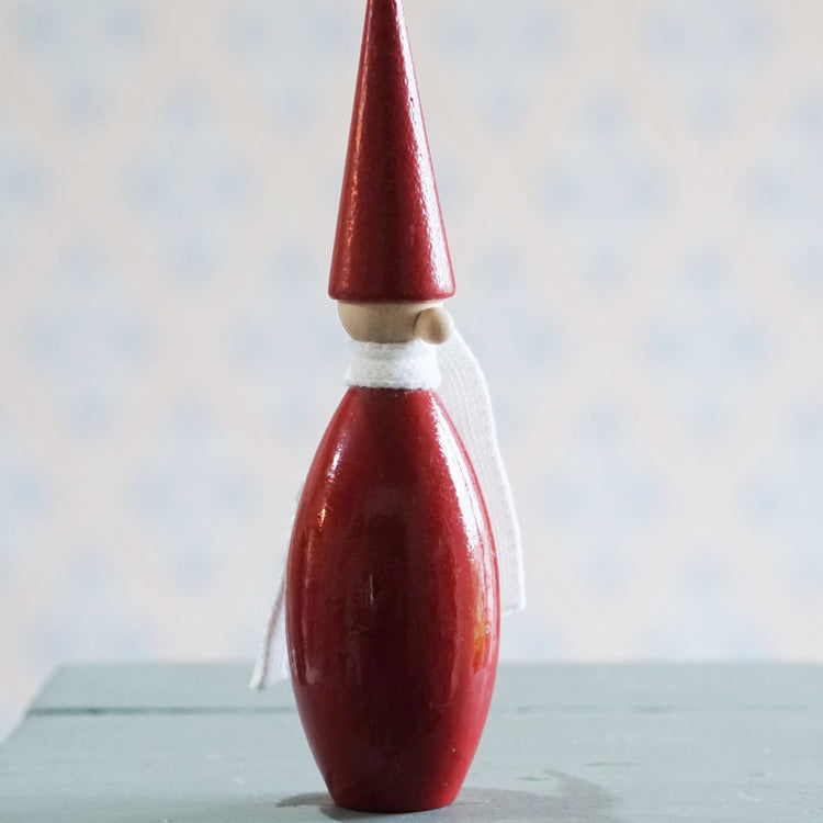 ein Wichtel in Kegelform aus Holz, rot mit weißem Schal und Kugelnase