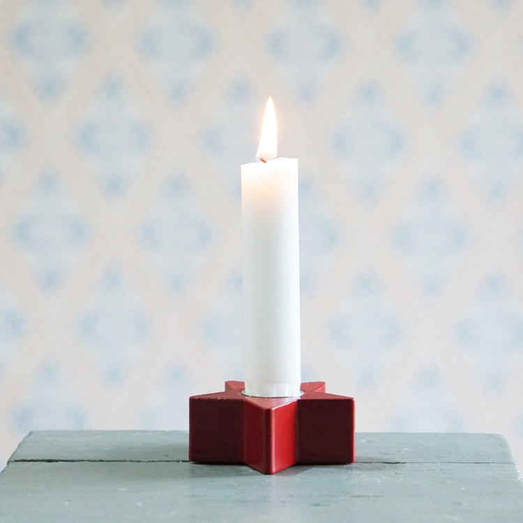 Kerzenhalter aus Holz in rot in Form eines Sterns mit brennender Kerze