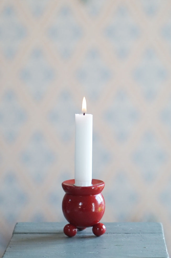 mittelgroßer Kugelleuchter aus Holz in rot mit brennender Kerze