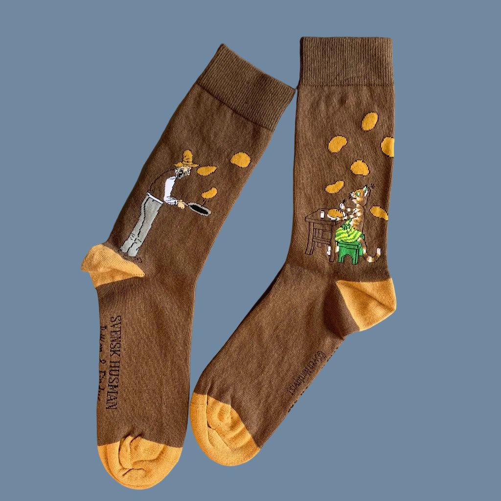 Braune Socken mit orangen Spitzen und Fersen und Findus und Pettersson auf je einer Socke mit Pannkuchen