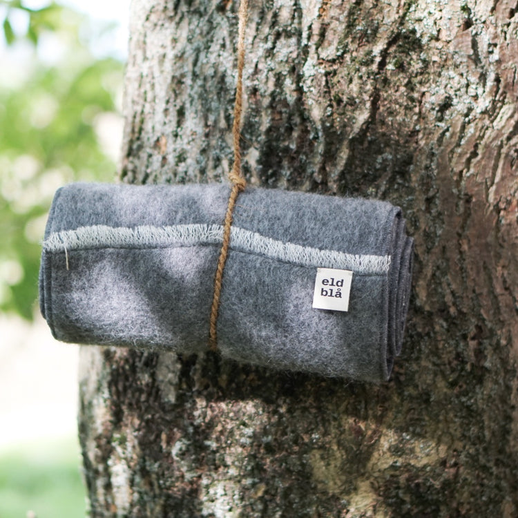 Sitzunterlage aus Gotlandwolle zusammengerollt am Baum hängend