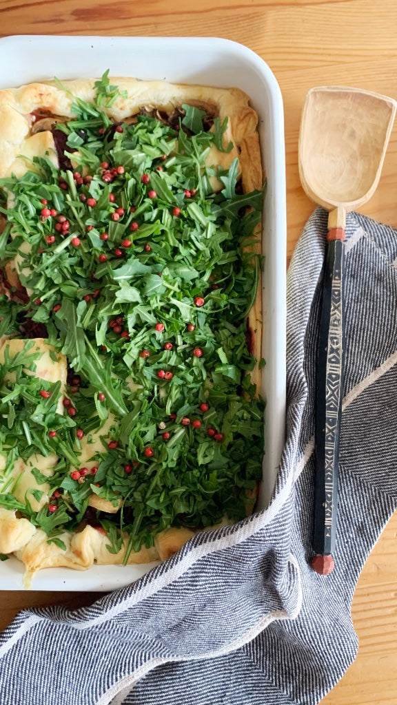 Blick von oben auf gefüllte Auflaufform mit Handtuch an der Seite und Servierlöffel