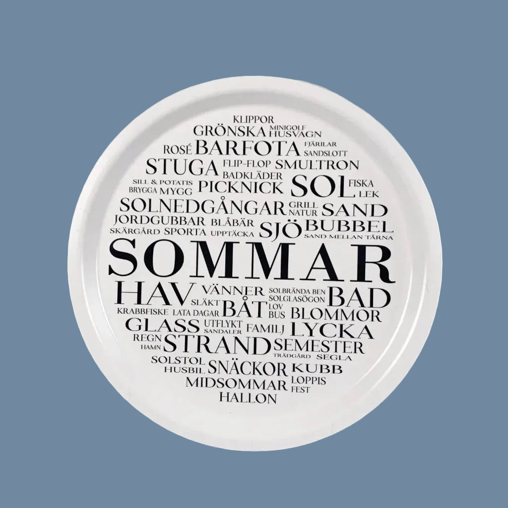 Rundes Tablett in weiß mit schwarzer Schrift, mittig steht Sommar, drumherum stehen in unterschiedlichen Größen Wörter auf schwedisch, die mit Sommar zu tun haben wie z. Bsp. sjö, båt, semester usw.