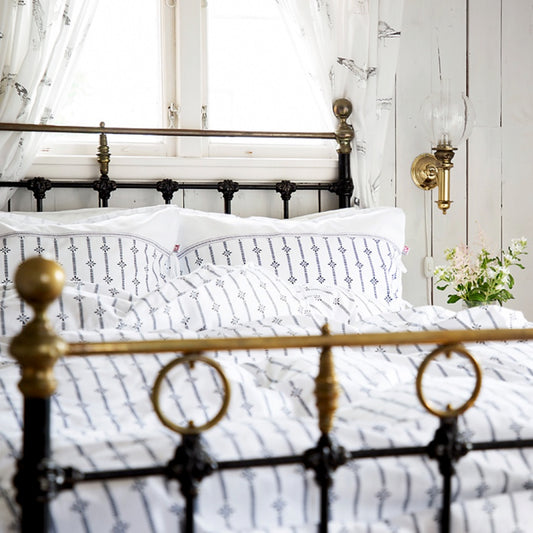 Metallbett mit goldener Oberkante in dem Bettwäsche Stripe liegt