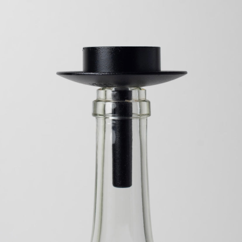 Teelichthalter aus Metall schwarz auf weißer Glasflasche