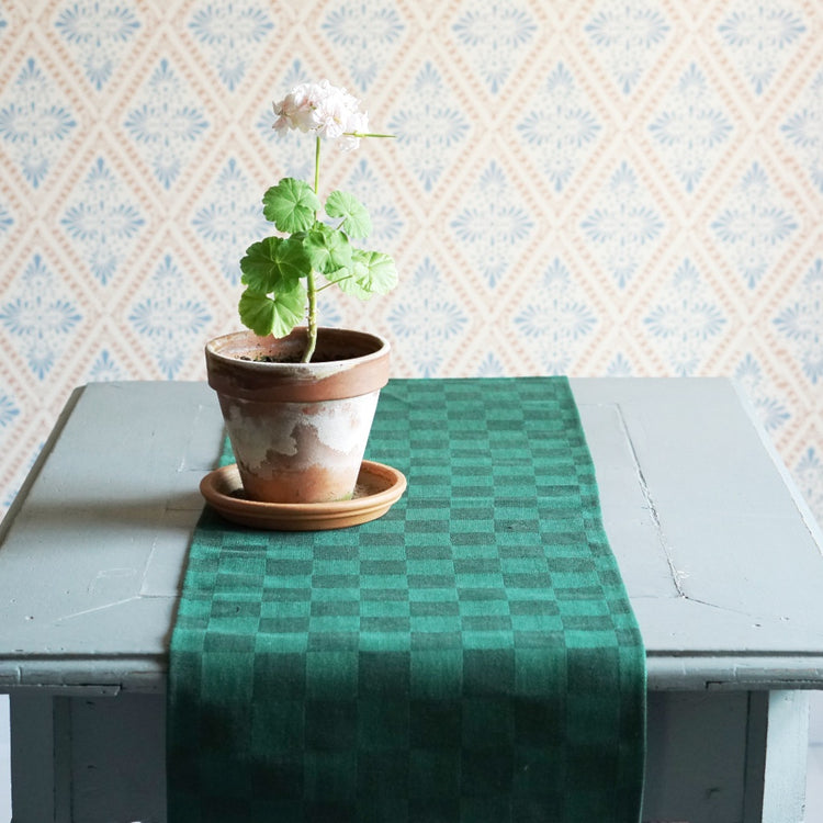 Tischläufer Karo in grün auf Tisch mit Pelargonie im Topf drauf