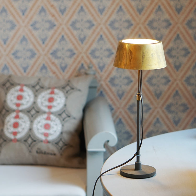 Tischlampe Karl klein auf Tisch neben Küchensofa mit einem Leinen Kissen, im Hintergund Wand mit typisch schwedischer Tapete