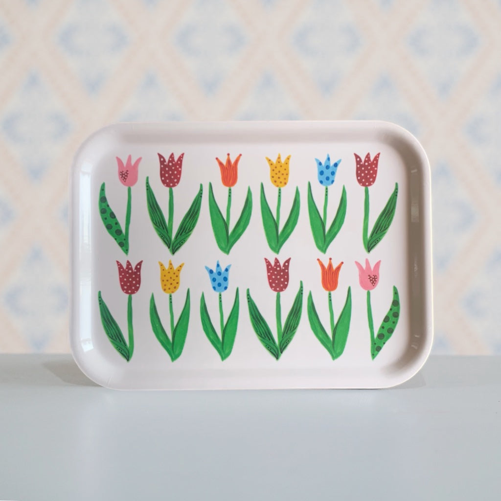 Eckiges Holztablett mit bunten Tulpenillustrationen in Reihe stehend auf Tisch vor Schwedentapete