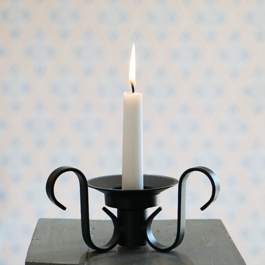 Kerzenhalter Vändbar mit brennender Tafelkerze, der Halter sitzt zwischen den Füßen