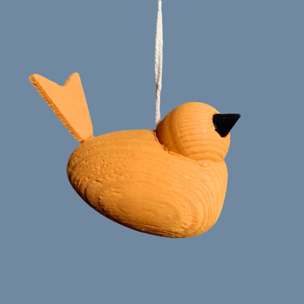 kleiner orangefarbener Holzvogel an weißem Band vor mysblauem Hintergrund