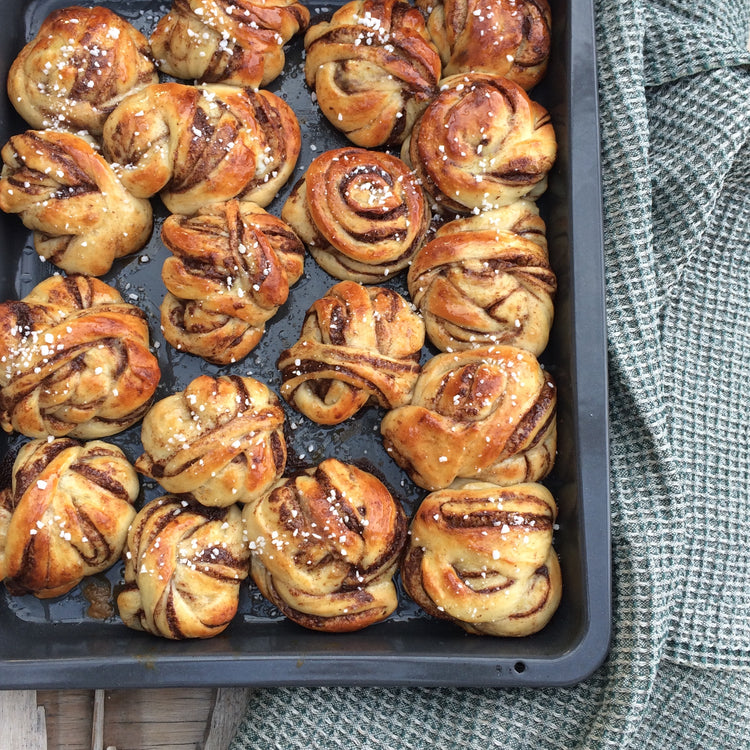 Blech voller Zimtschnecken von oben mit Handtuch Bubbel an Seite