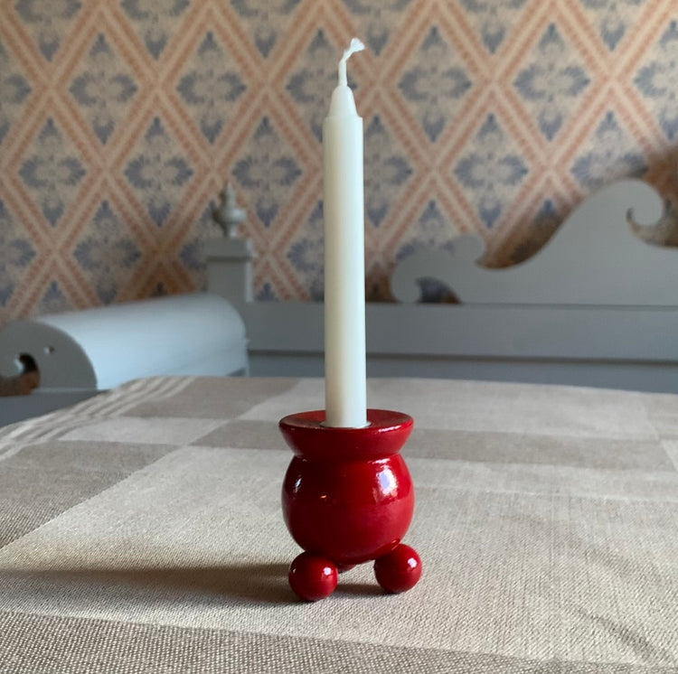 Traditioneller schwedischer Kugelkerzenhalter in rot auf einer Leinentischddecke vor einer Küchenbank