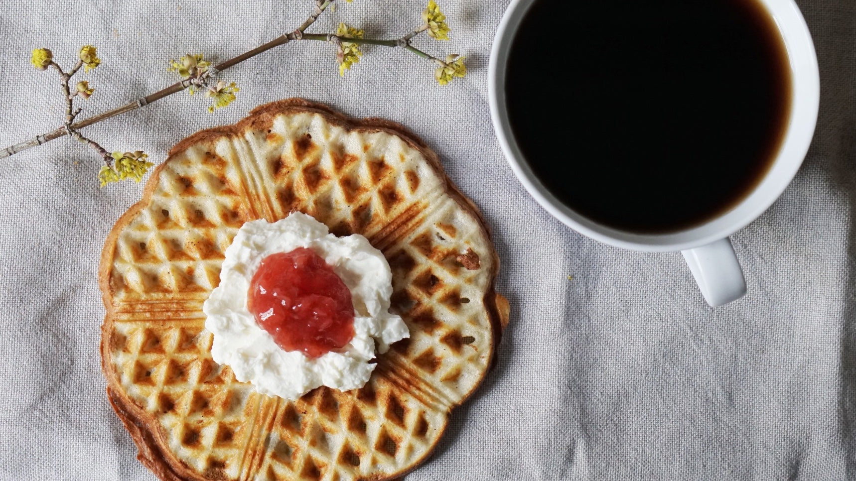 Waffel mit Schlagsahne und Marmelade und Kaffeetasse von oben