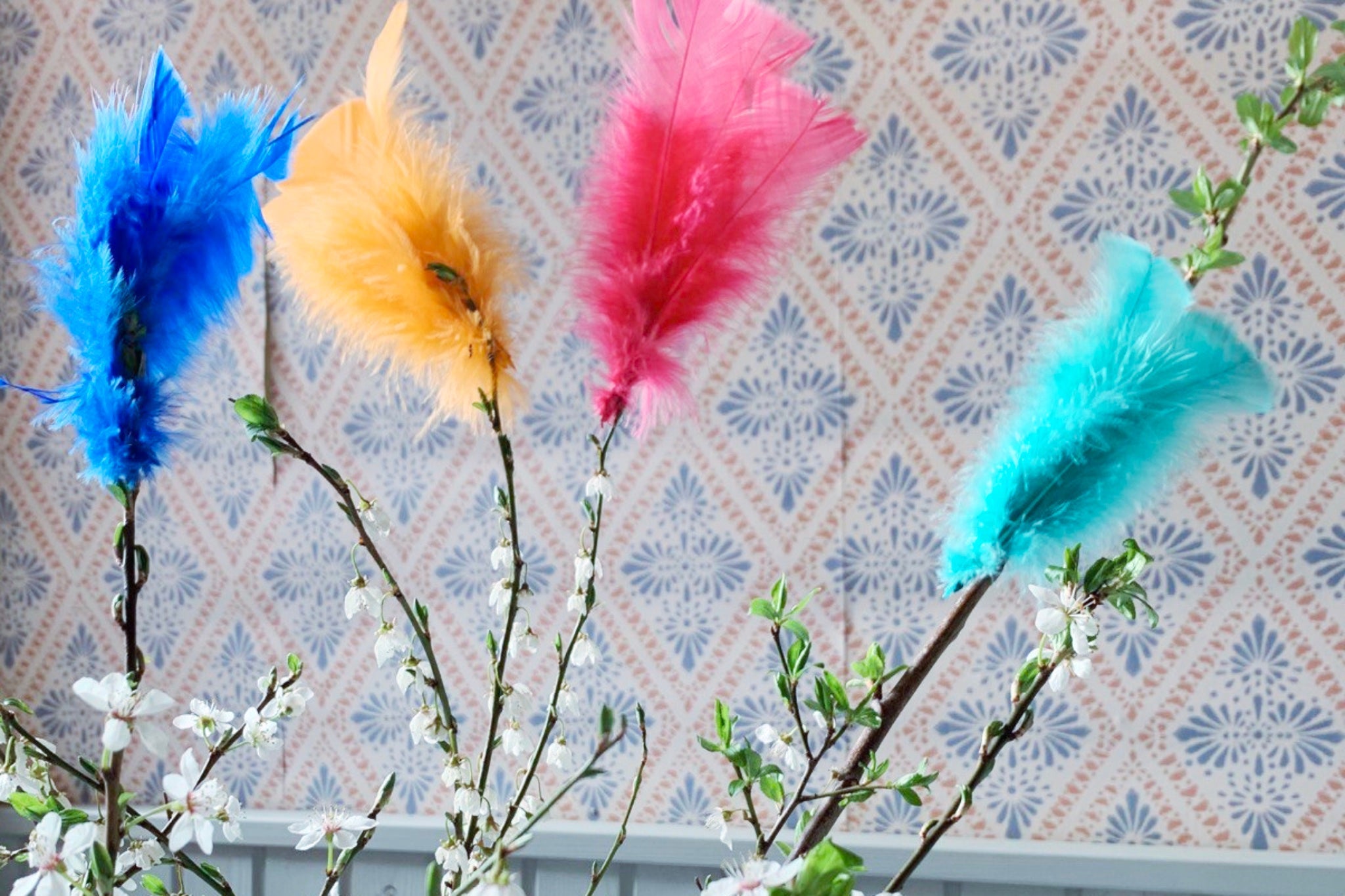Bunte Federn als Osterdekoration an Zweigen in Schweden