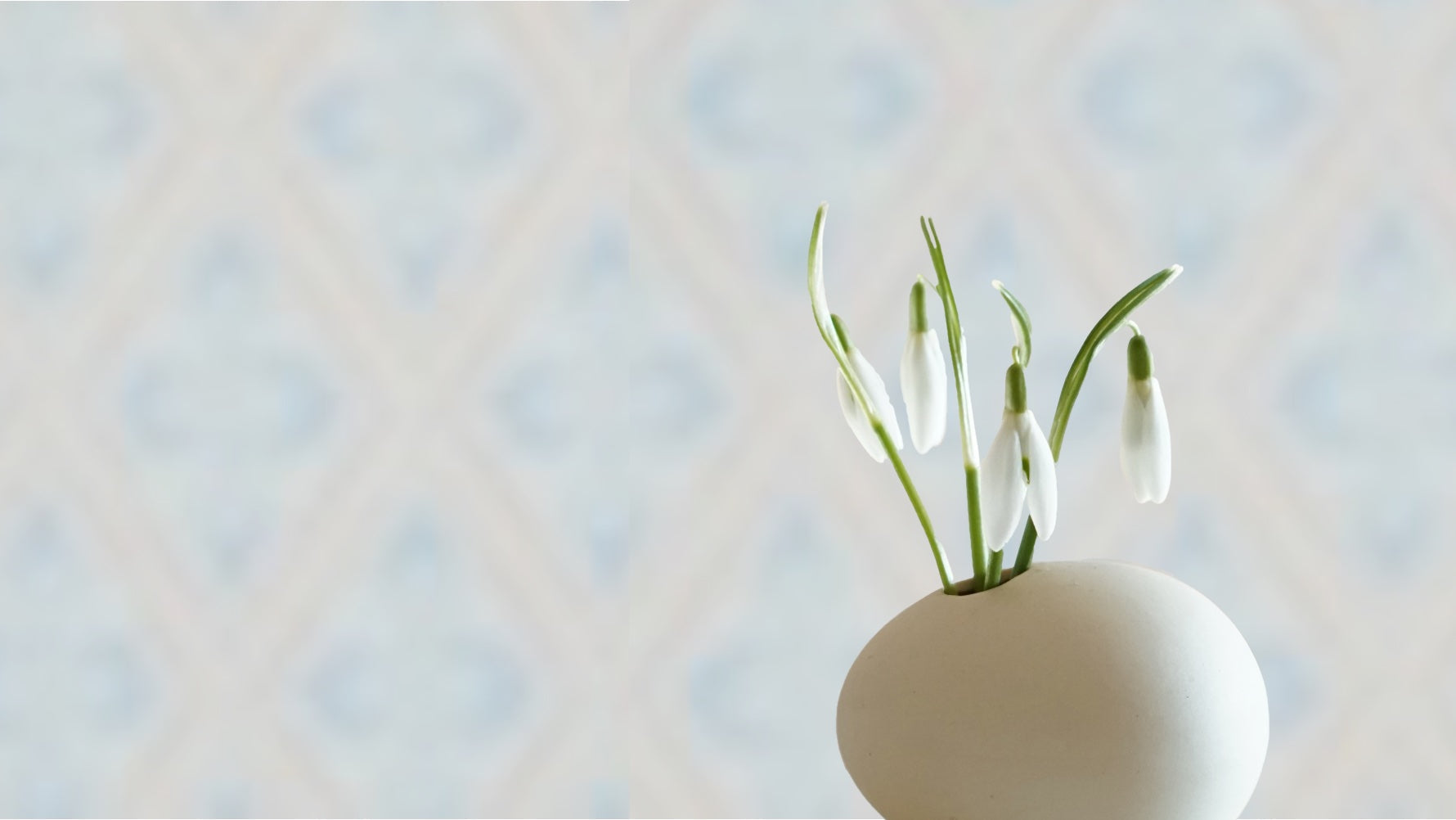 Keramikvase mit Schneeglöckchen vor Schwedentapete