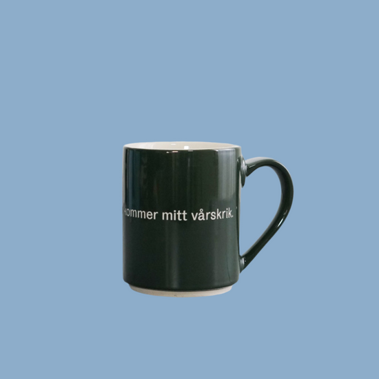 Tasse aus Steingut mit Spruch Håll för örona. För nu kommer mitt vårskrik vor blauem Hintergrund