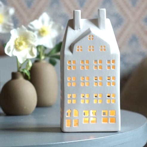 Städtische Villa aus weißer Keramik von innen leuchtend, im Hintergrund weiße Christrosen