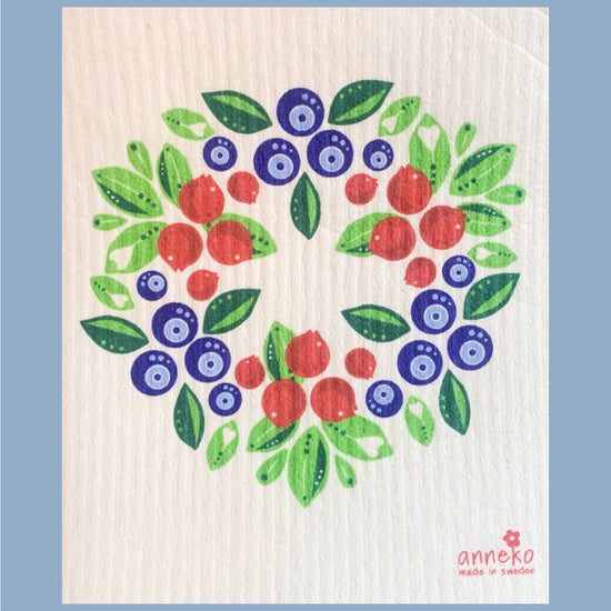 Illustrierter Kranz aus Blaubeeren und Preiselbeeren und grünen Blättern, in der unteren rechten Ecke steht das Logo von Anneko