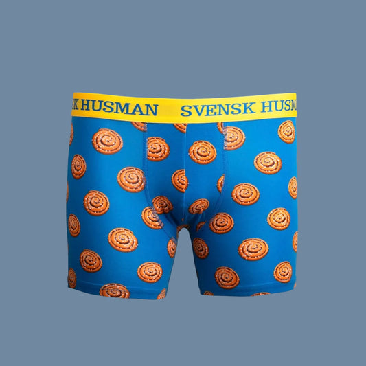 blaue Boxershorts mit runden Zimtschnecken nd gelbem Gummibund vor mysblauem Hintergrund