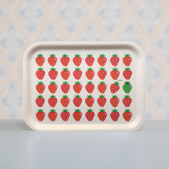 Holztablett mit fünf Reihen roter Erdbeere, eine davon ist grün