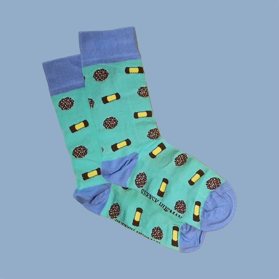 zwei Socken in grün mit blauem Bündchen, Ferse und Zehenspitze mit Punschrollen und Schokobällen drauf