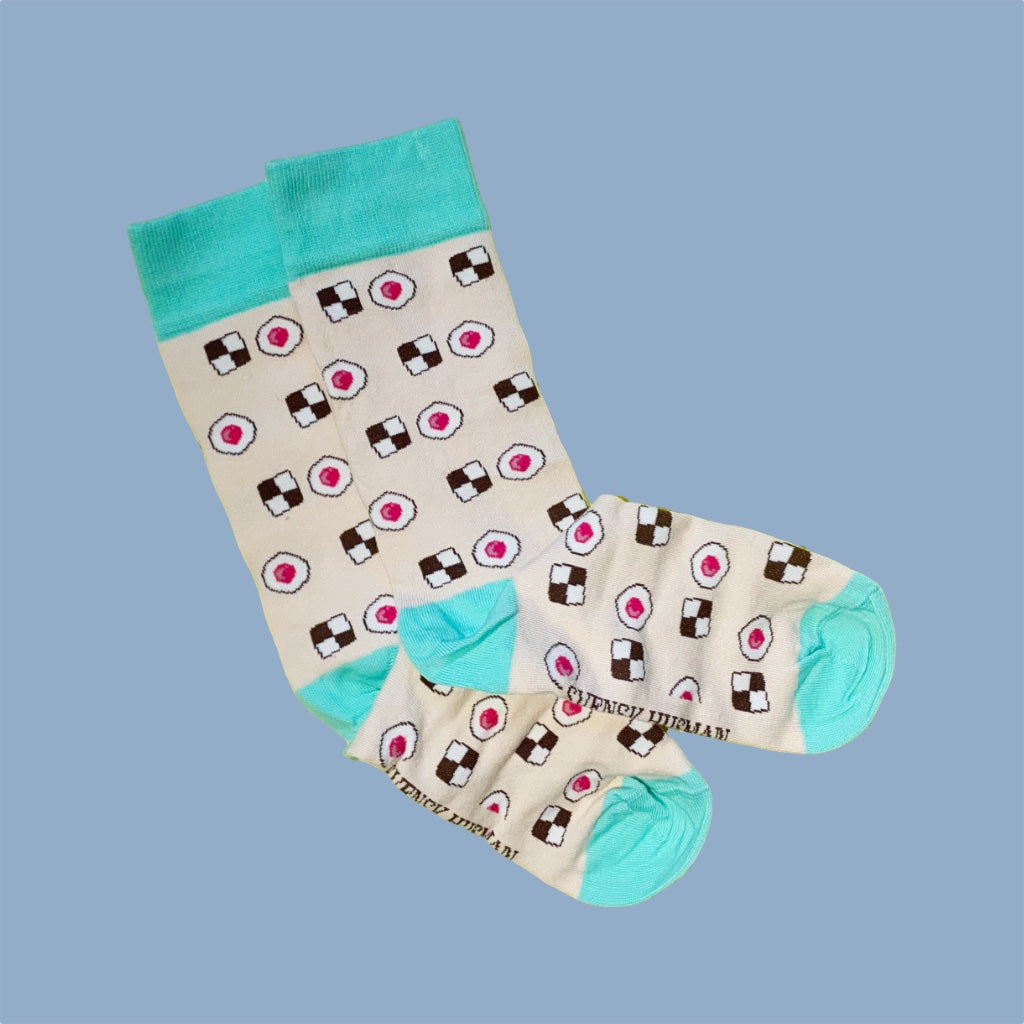 zwei Socken in beige mit grünem Bündchen, Ferse und Zehenspitze mit Keksen und Himbeerhöhlen drauf