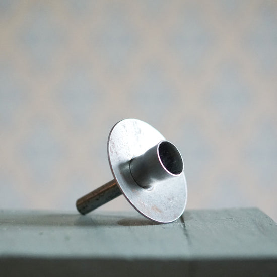 Kerzenhalter Flaska schmal aus Metall unbehandelt auf einem Tisch liegend
