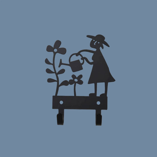 Hakenleiste aus Metall Gärtnerin schwarz vor mysblauem Hintergrund