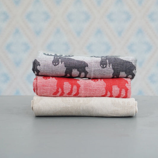 Geschirrtuch mit Elchen aus Halbleinen rot, schwarz, natur im Stapel vor Schwedentapete