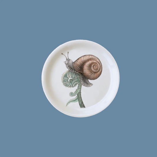 Glasuntersetzer mit Schnecke mit Haus auf einem zusammengerollten Farnblatt