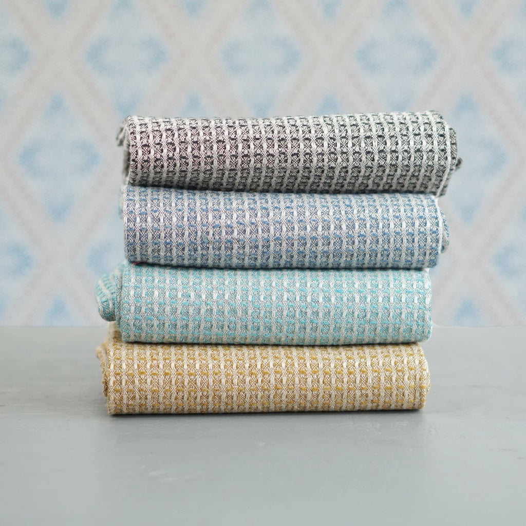 vier Handtücher Bubbel aus Leinen im Stapel vor Schwedentapete