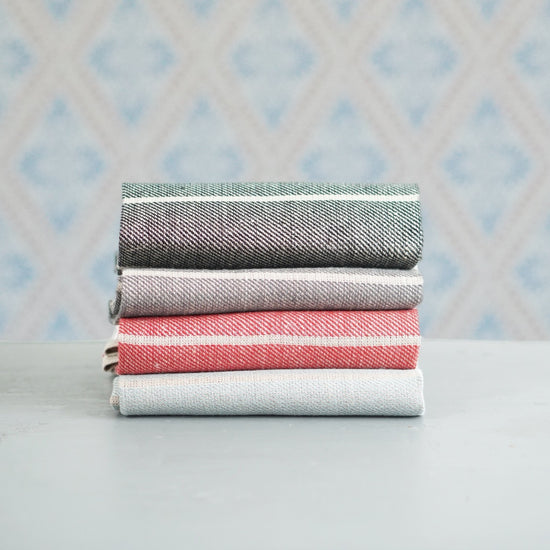 vier Handtücher Ingela aus Leinen im Stapel vor Schwedentapete