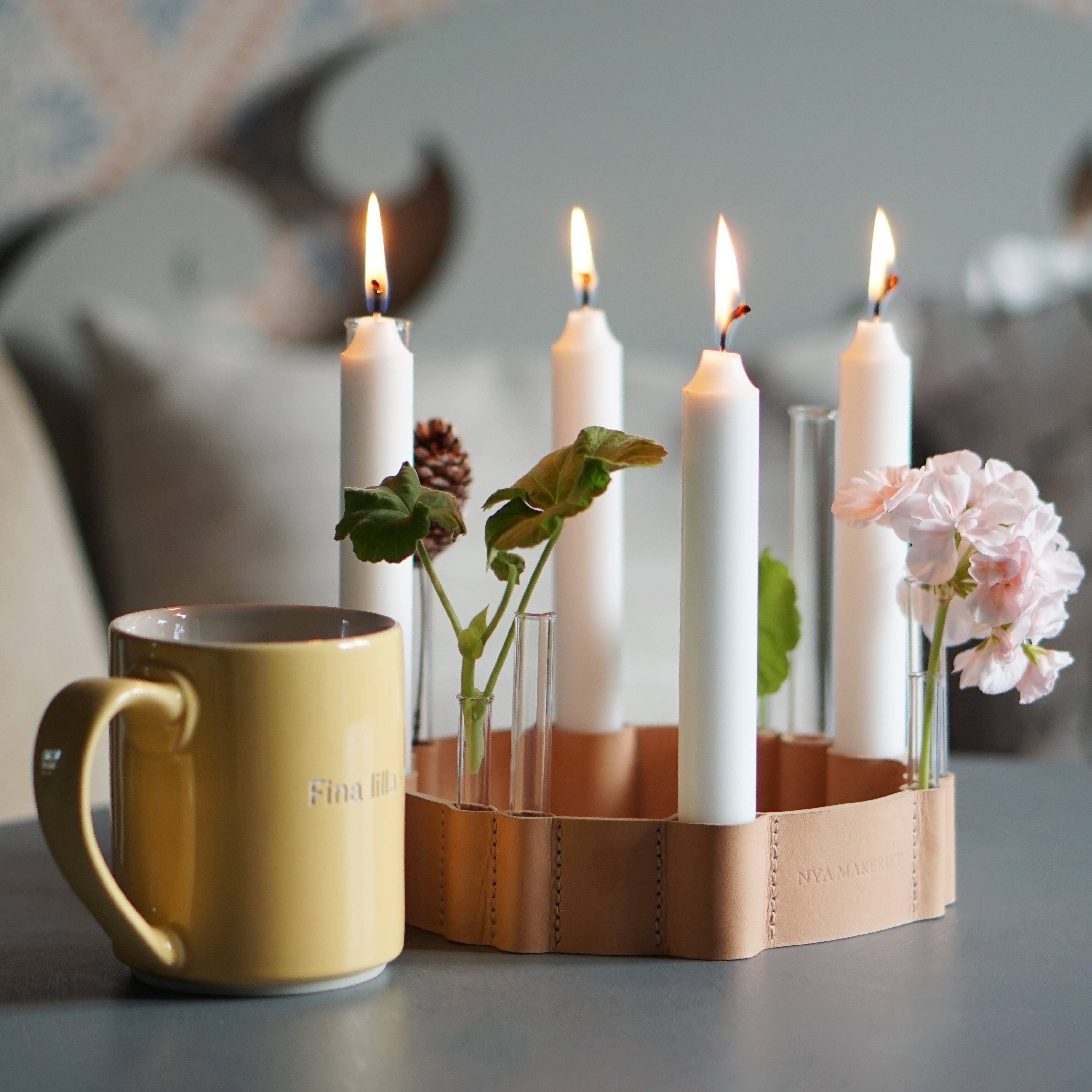 Kerzenständer aus Leder mit vier brennenden Kerzen und einer Kaffeetasse