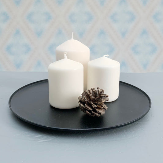 Kerzenteller Ljusfat Kerzenhalter für Blockkerzen Metall schwarz mit drei Blockkerzen und Kiefernzapfen auf Tisch